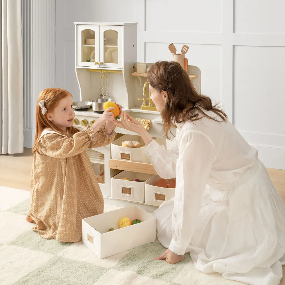 Woman and child playing with toy kitchen set in a bright room