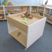 Children's play area with a wooden sensory table and shelves in a classroom setting.