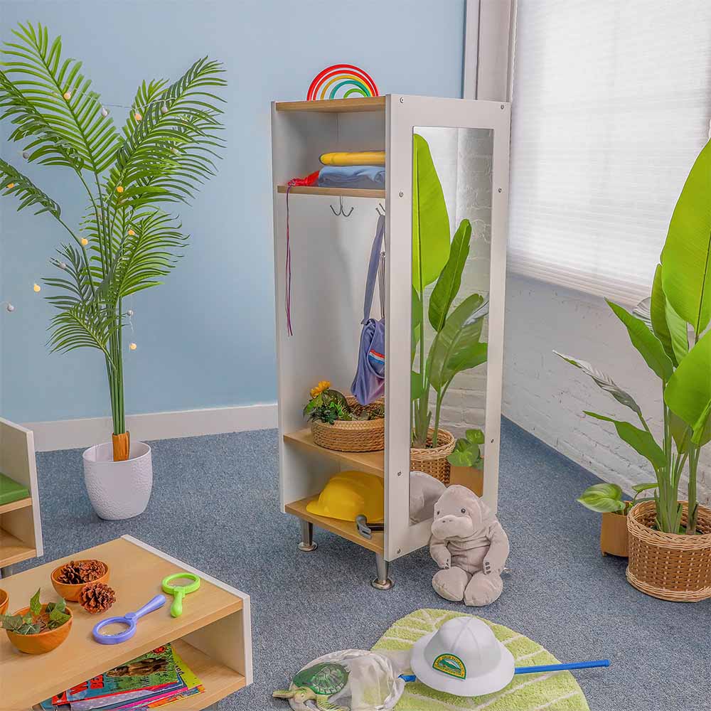Children's playroom with a dress-up wardrobe unit, plants, and toys on the floor.