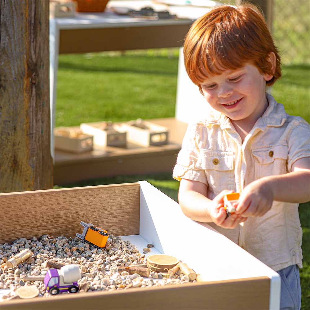 Child playing with toys in a big and wide table outdoors