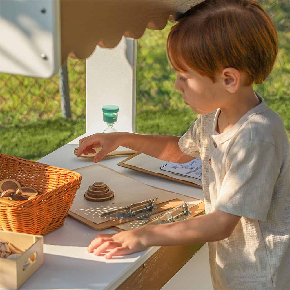 Child playing with accessories in a play market stand outside