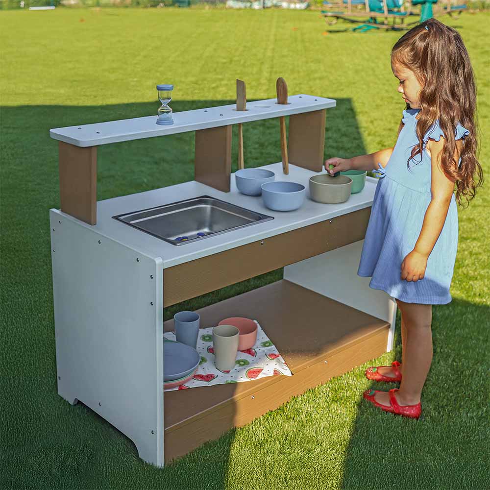 Child playing with a outdoor play mud kitchen set on grass
