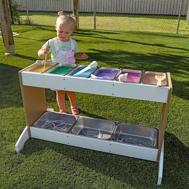 Child playing with a colorful potion station on grass