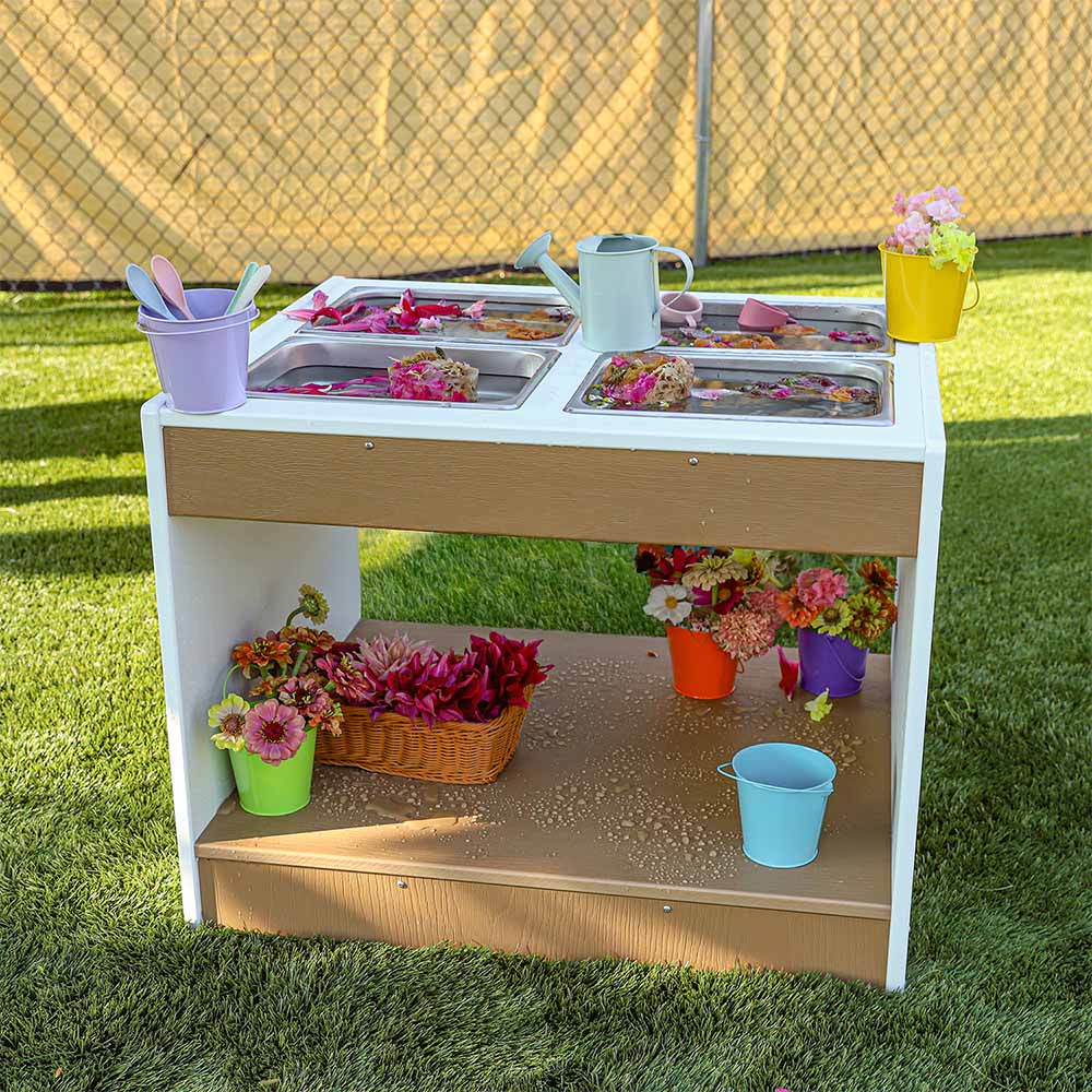 Children's sensory table with various items on a grassy area